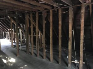 A room undergoing demolition and clean-out, showing exposed studs and a ladder, by Junk Removal and More LLC in Columbus, OH.
