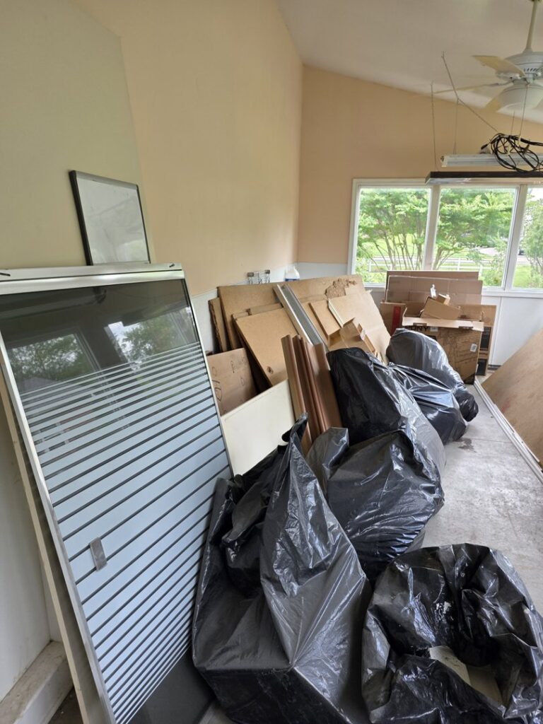 A room filled with large black trash bags, wood, and debris ready for junk removal by GEF Hauling and Junk Removal in Philadelphia, PA.