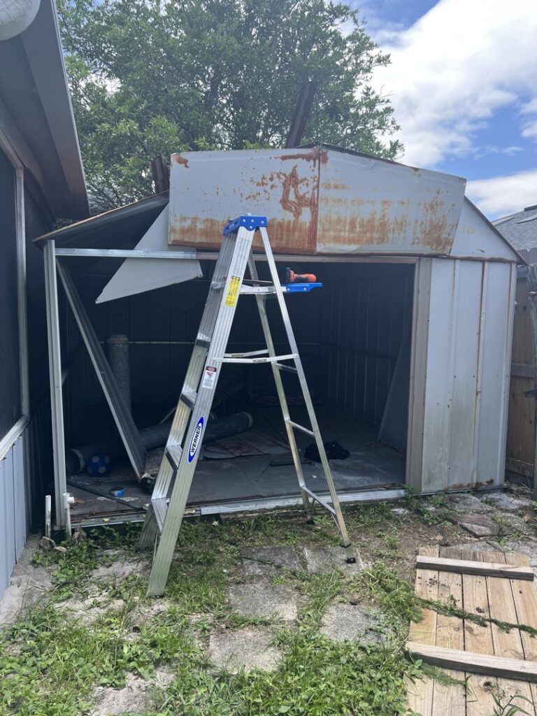 A metal shed undergoing demolition, showing the shed removal service by Junk Fade Away, LLC in Jacksonville, FL.