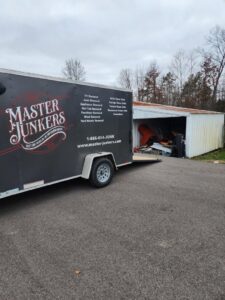 A Master Junkers trailer parked next to a shed filled with junk, ready for cleanout in Powell, OH.