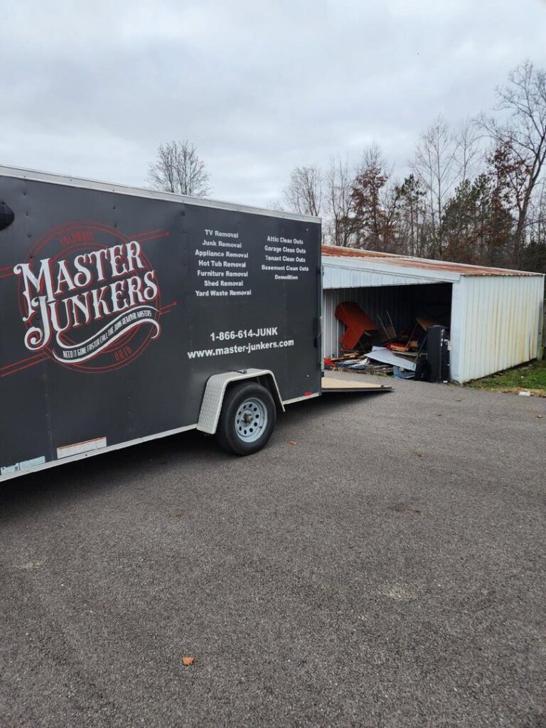 A Master Junkers trailer parked next to a shed filled with junk, ready for cleanout in Powell, OH.
