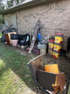 A large pile of mixed debris and junk in a side yard, ready for removal by Clear Your Junk - Pearland in Houston, TX.