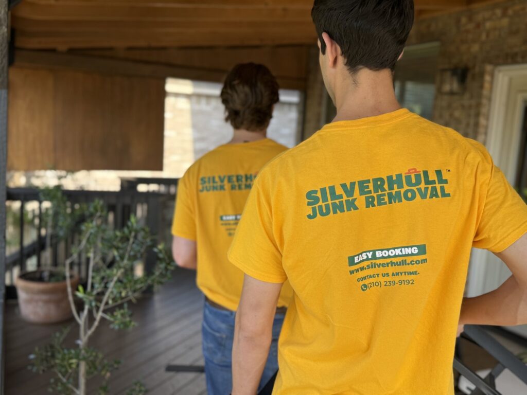 Two Silverhull Junk Removal employees in branded shirts walking on a job site in San Antonio, TX.