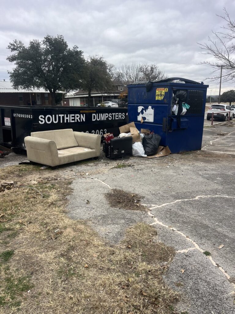 A sofa and other household junk piled next to dumpsters, ready for removal by NTX Haul Away Junk Removal in Fort Worth, TX.