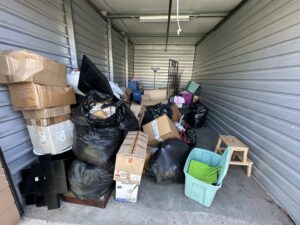 A cluttered storage unit filled with boxes and trash, indicating a cleanout job by Haul Away Any Day in San Diego, CA.