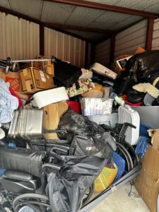 A cluttered storage unit packed with boxes, furniture, and various items, ready for cleanout by Handymen Junk Removal in Houston, TX.