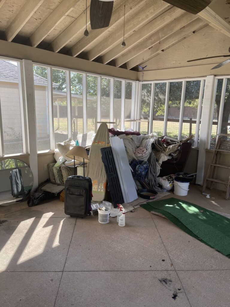 A sunroom filled with household clutter and old furniture, awaiting junk removal by G.I. HAUL in Austin, TX.
