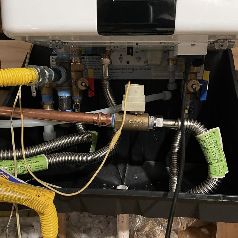 Close-up of the intricate pipe connections and valves for a tankless water heater, installed by Tribeca Plumbing in Dallas, TX.