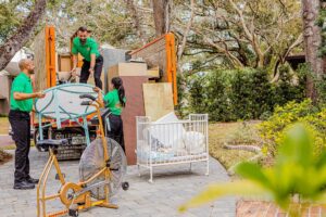 College Hunks team loading large items like a crib and exercise bike into a junk removal truck in Jacksonville, FL