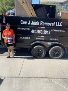 A Cee J Junk Removal LLC team member standing next to a loaded junk removal trailer in Phoenix, AZ.