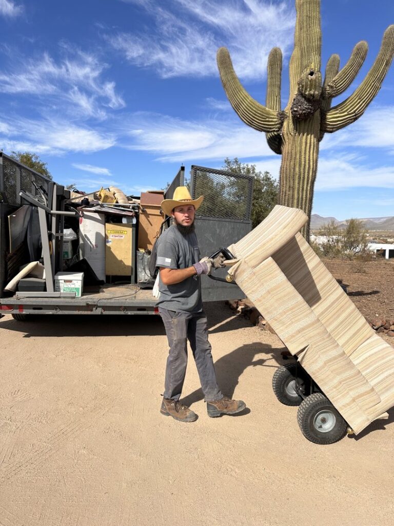 A North Valley Junk Removal team member using a dolly to move large furniture for removal in Phoenix, AZ.