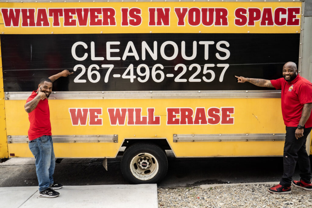 Two Space Erasers Junk Removal team members standing proudly next to their branded truck in Philadelphia, PA