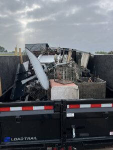A dump trailer filled with scrap metal, a satellite dish, and other junk by Junk Removal of Hancock County in Indianapolis, IN.