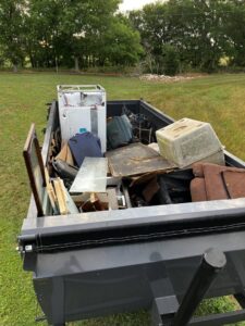A junk removal trailer loaded with an old washing machine, furniture, and various debris by Junkie 4 Jesus Junk Removal in Austin, TX