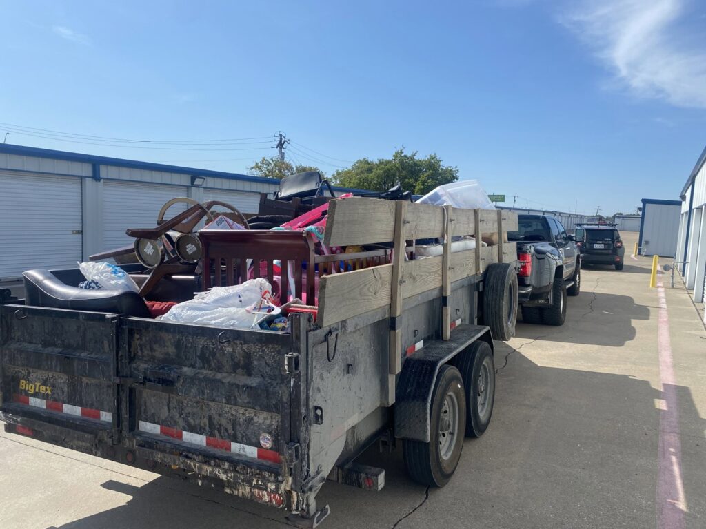 A trailer loaded with assorted household junk items, parked near storage units for removal by Perez Junk Removal in Anaheim, CA.