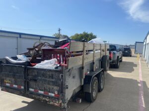 A trailer loaded with assorted household junk items, parked near storage units for removal by Perez Junk Removal in Anaheim, CA.