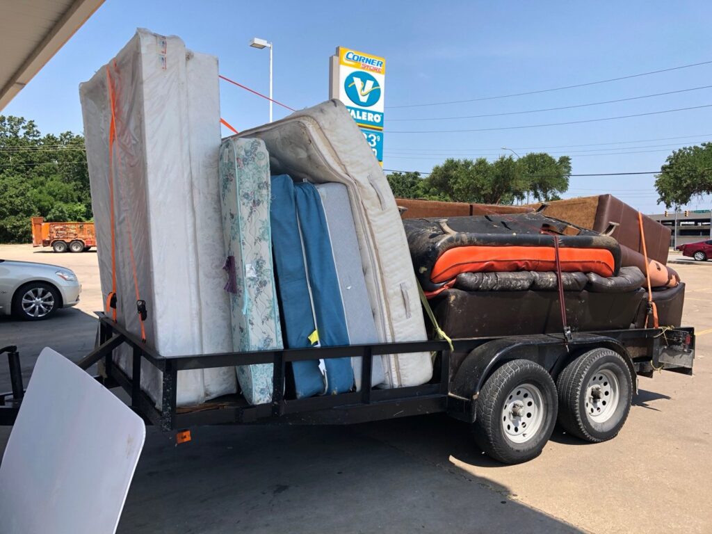A trailer heavily loaded with various mattresses and furniture items, ready for disposal by Perez Junk Removal in Anaheim, CA.