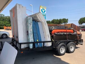 A trailer heavily loaded with various mattresses and furniture items, ready for disposal by Perez Junk Removal in Anaheim, CA.