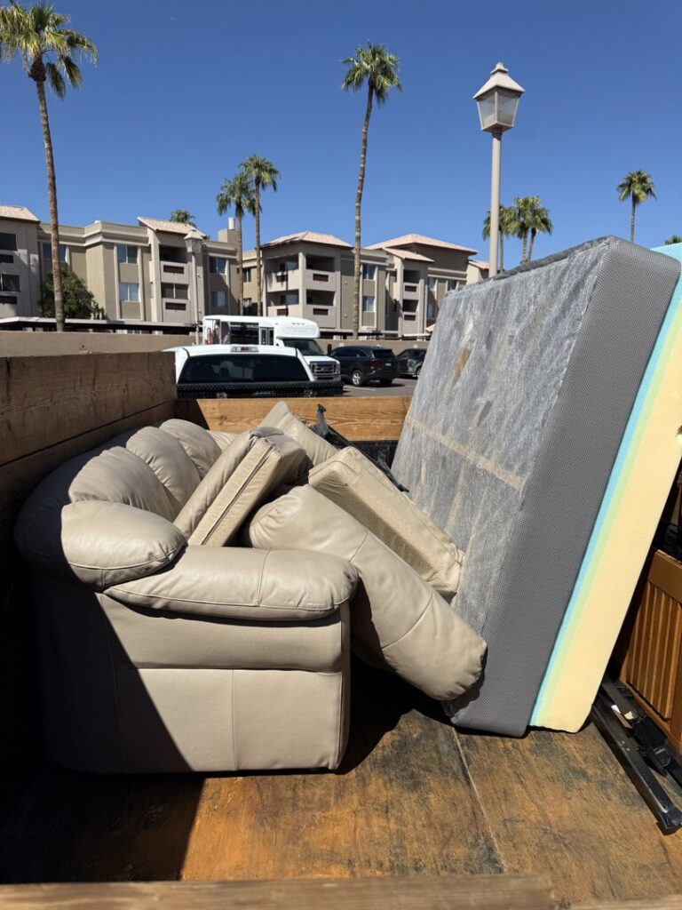 A Minutemen Junk Removal trailer loaded with a sofa, mattress, and other furniture for disposal in Phoenix, AZ.