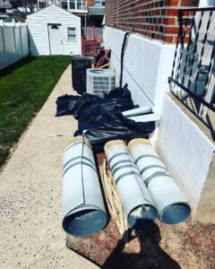 A pile of trash bags and insulation debris next to a building for removal by S&M Junk Removal in Philadelphia, PA.