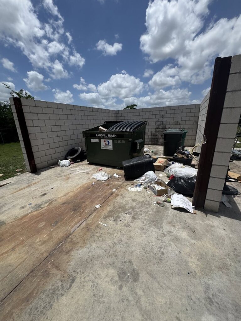 Trash bags and debris scattered around a dumpster, showing a messy site for junk removal by Junk Out Boyz LLC in Austin, TX.