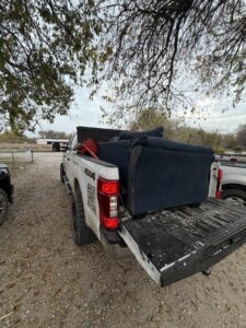 A City to City Junk Removal truck bed filled with a blue sofa for disposal in Fort Worth, TX.
