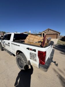 A City to City Junk Removal truck bed filled with cardboard boxes and other items for disposal in Fort Worth, TX.