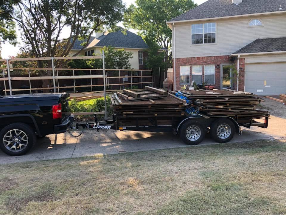 A pickup truck pulling a trailer loaded with old wooden fence panels and construction debris for removal by Perez Junk Removal in Anaheim, CA.