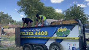 Two JunkGuys Austin Junk Removal employees are actively loading various debris and junk into a trailer in Austin, TX.