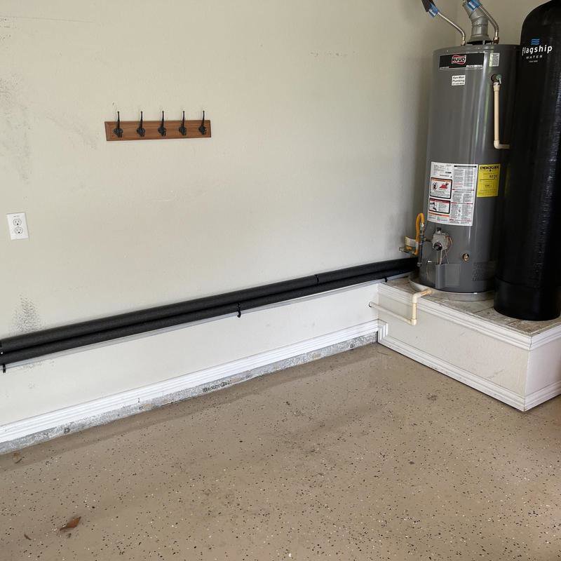 A water heater and water softener system installed in a garage, demonstrating plumbing services by Tribeca Plumbing in Dallas, TX.