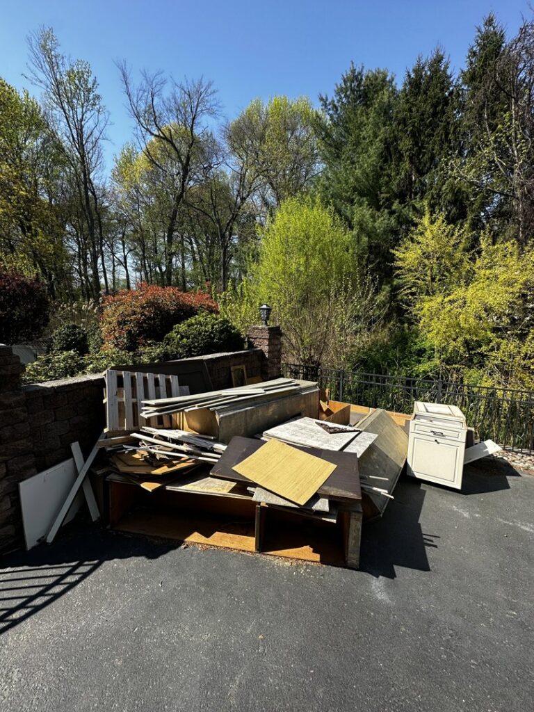 A large pile of wood and furniture debris in a driveway for removal by S&M Junk Removal in Philadelphia, PA.