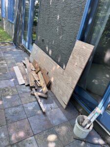 A pile of wood planks and plywood debris next to a patio, ready for removal by GEF Hauling and Junk Removal in Philadelphia, PA.