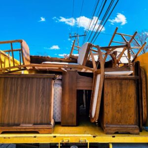 A Junk to Go truck bed filled with wooden furniture like dressers and chairs for removal in Philadelphia, PA.