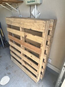 A stack of wooden pallets in a garage, ready for removal by Faithful Hands Junk Removal in San Antonio, TX.