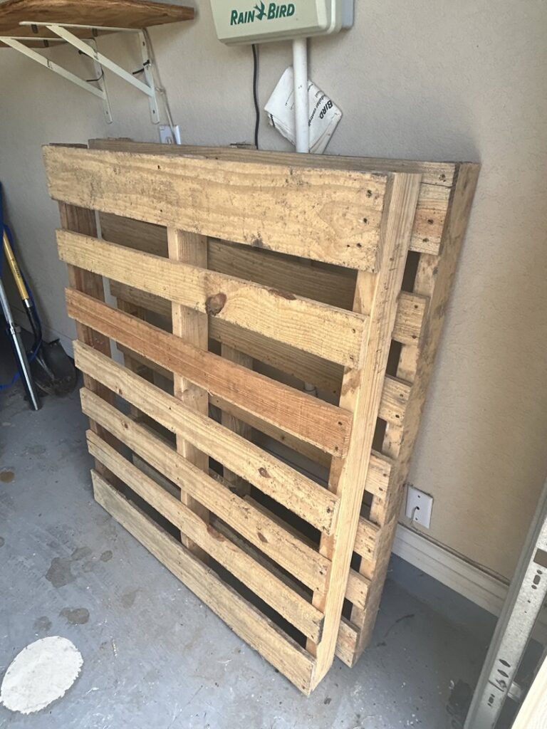 A stack of wooden pallets in a garage, ready for removal by Faithful Hands Junk Removal in San Antonio, TX.