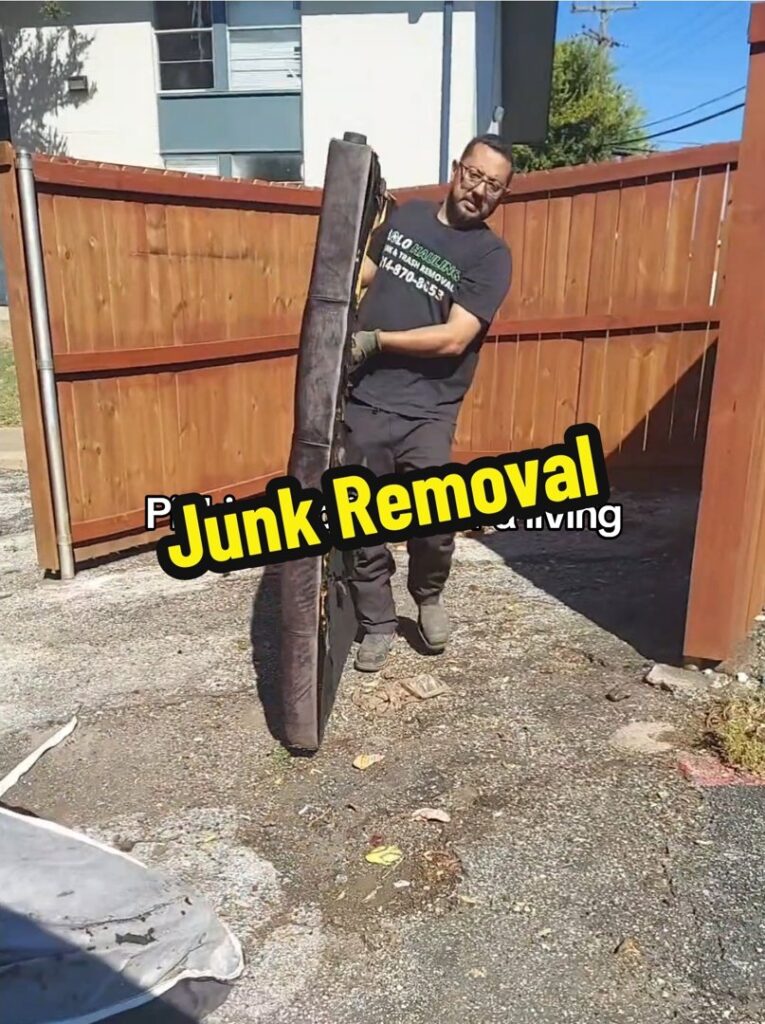 A Lolo Hauling Junk Removal worker carrying a large piece of furniture for removal in Dallas, TX.