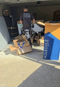 A Lolo Hauling Junk Removal worker clearing debris and cardboard boxes from a garage in Dallas, TX.