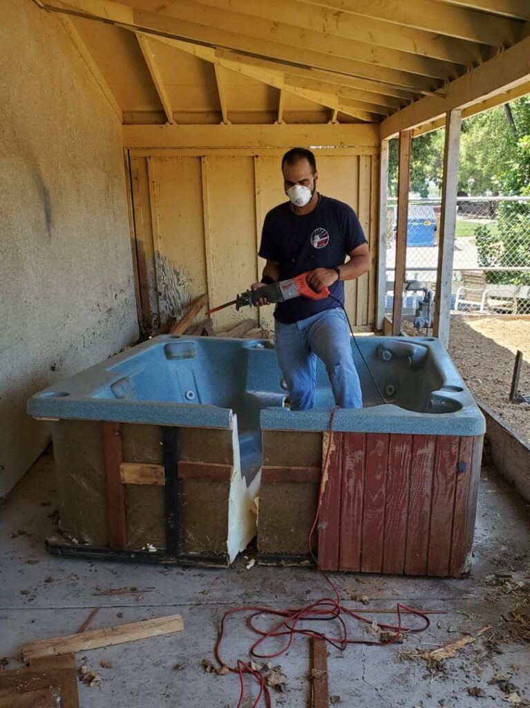 A worker cutting an old hot tub for removal by Strong Hands Hauling & Dumpster Rental in San Jose, CA