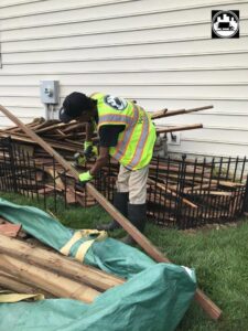 A worker from We Haul It Cleaning Service LLC in Canal Winchester, OH, cutting wood during a yard debris removal job.
