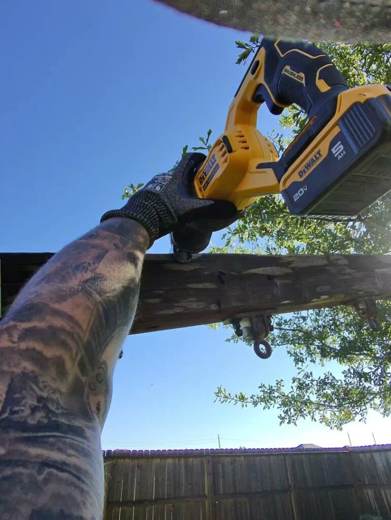 A Clutch City Junk Removal worker cutting a wooden beam during a demolition and junk removal job in Tomball, TX.