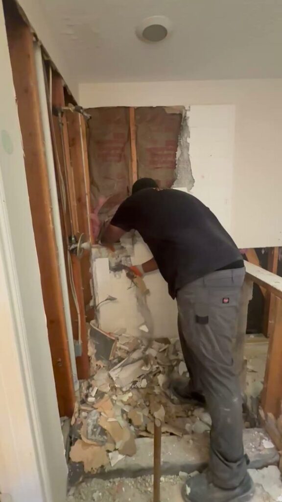 A Clutch City Junk Removal team member performing interior wall demolition and debris removal in Tomball, TX.
