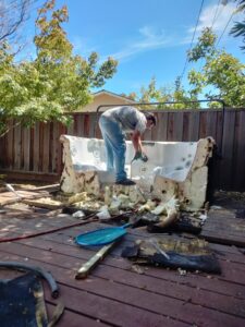 A worker dismantling an old hot tub on a deck for Strong Hands Hauling & Dumpster Rental in San Jose, CA