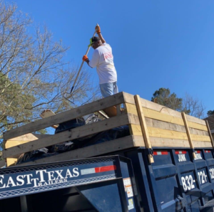 A worker on top of a junk removal trailer, loading debris for McMillian Junk Removal in Houston, TX
