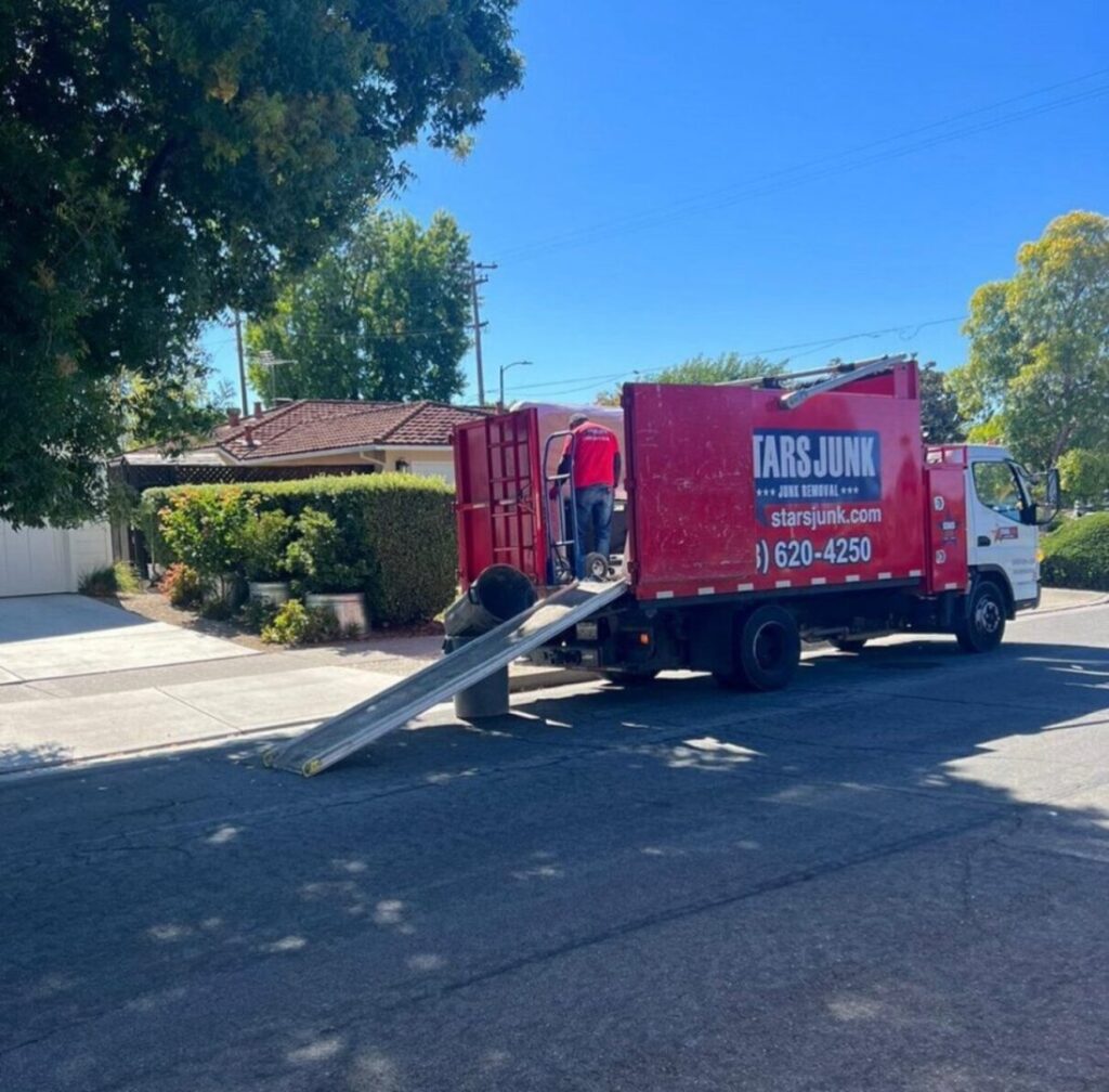 A worker loading junk into a Stars Junk Removal truck using a ramp during a job in San Jose, CA