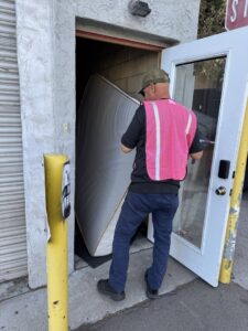 A worker from Fred's Junk Removal moving a mattress into a doorway for removal in Chula Vista, CA.