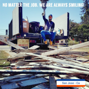 A worker on a junk removal truck with a large pile of wood debris in San Jose, CA by Strong Hands Hauling & Dumpster Rental