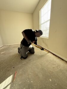 A Clutch City Junk Removal team member removing baseboards and flooring during a cleanout job in Tomball, TX.