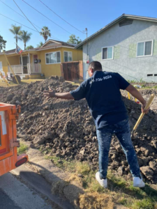 A worker shoveling a large pile of dirt and construction rubble for Dos Muchos Junk Removal LLC in San Diego, CA.