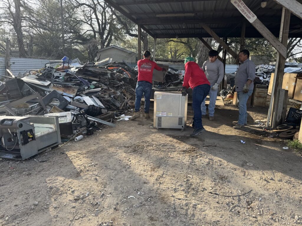 Speedy Junk Removal & recycling workers moving scrap metal at a recycling facility in Houston, TX.
