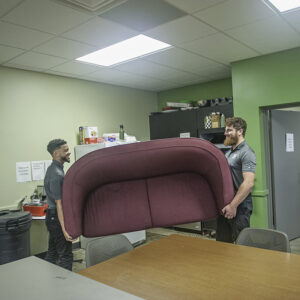 Two workers from Two Men and a Junk Truck carrying a sofa out of a building during a junk removal service in Columbus, OH.